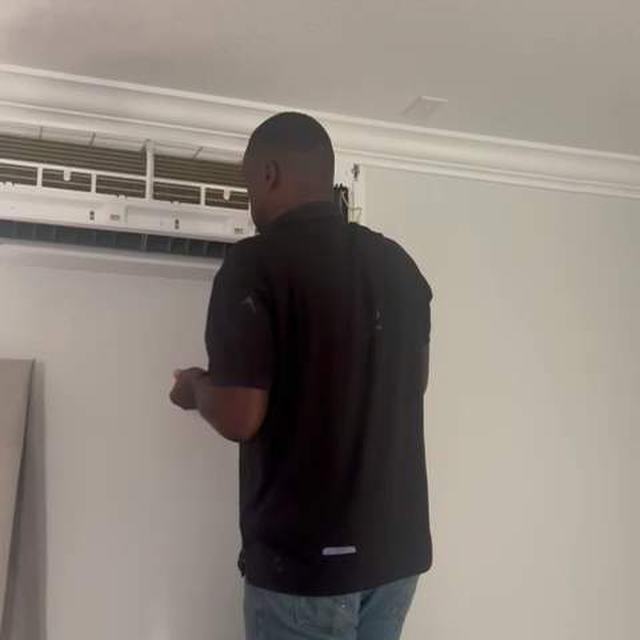 Technician servicing a wall AC unit